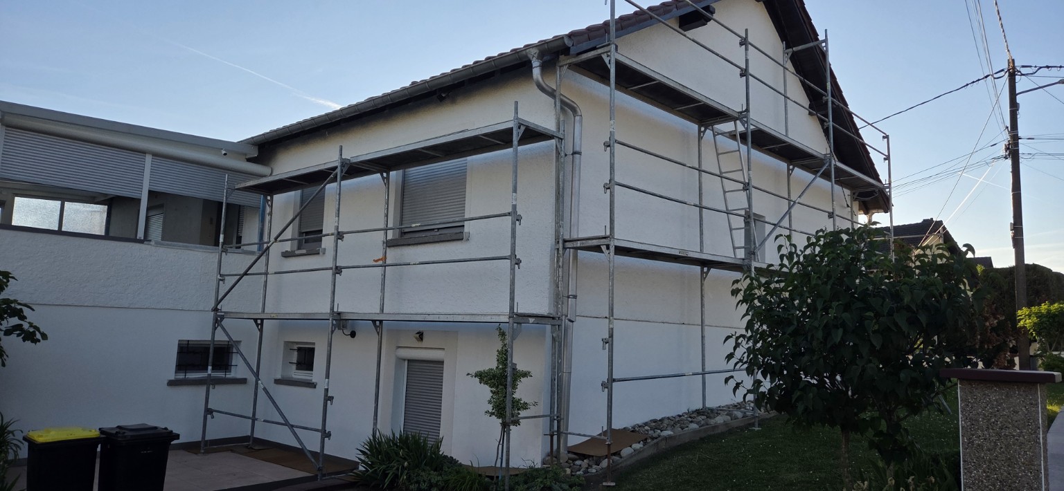 Maison avec échafaudage pendant travaux de colle et filet de façade